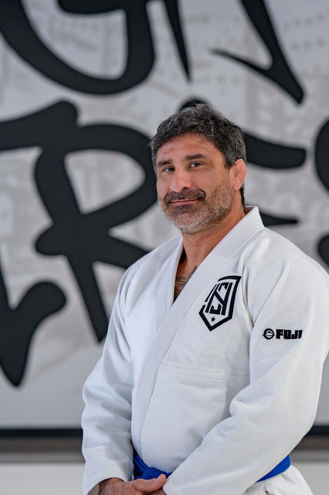 Coach Roberto Vargas in a white gi in front of the High Street mural